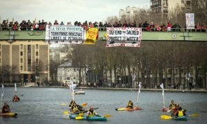 Indigenous people paddle down the Seine as others stand on a bridge holding banners during a rally in Paris demanding Indigenous rights are included in the climate accord on December 6, 2015 on the sidelines of the COP21 climate change conference. / AFP / LIONEL BONAVENTURELIONEL BONAVENTURE/AFP/Getty Images Photograph: Lionel Bonaventure/AFP/Getty Images